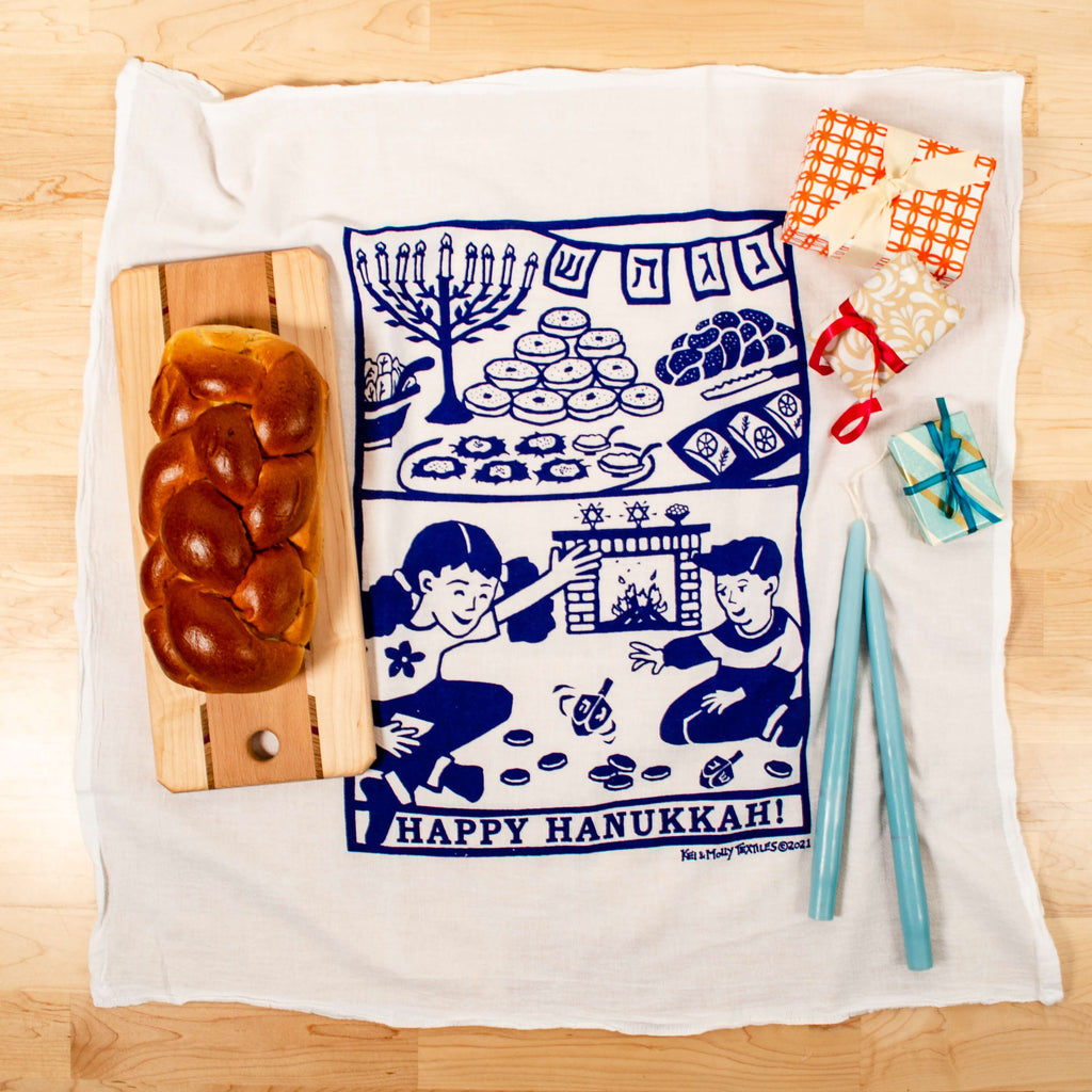 Kei & Molly Flour Sack Dish Towel, Happy Hanukkah! full view shown with Challah bread and gifts.
