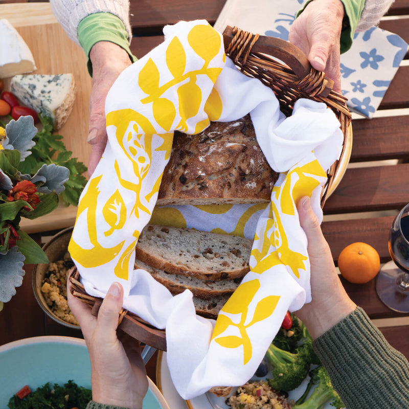 This photo shows a Kei & molly Pomegranate flour sack dish towel being used as a basket liner when serving bread.