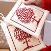 Two white potholders with red tree designs 