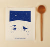 Kei & Molly Textiles Large Sponge Cloth Snowbirds design printed in Navy Blue: three birds in the snow under a night sky full of stars propped with a wooden spoon