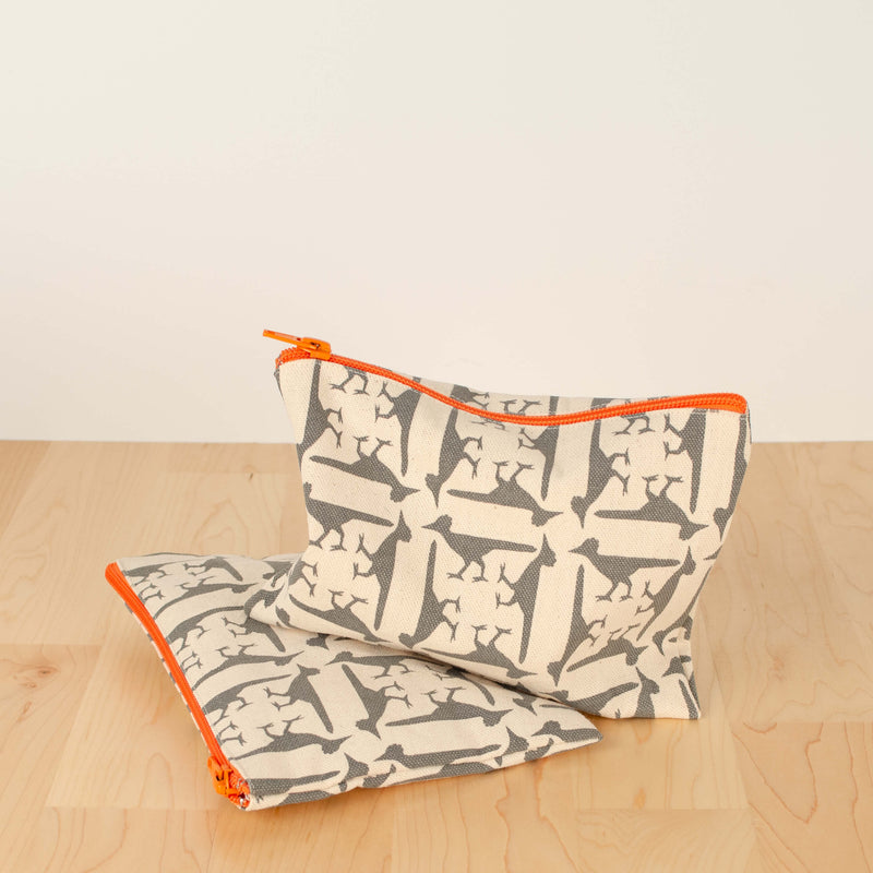Two Kei & Molly Cosmetic Bags with Roadrunners Design in Grey on wood with white background.