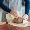 Bees wrap, reusable food wrap, bread wrap: honey comb print, showing bread being wrapped