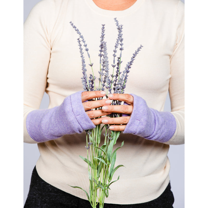 B. B Sheep cashmere fingerless gloves in lilac. Model holding a lavender bouquet.